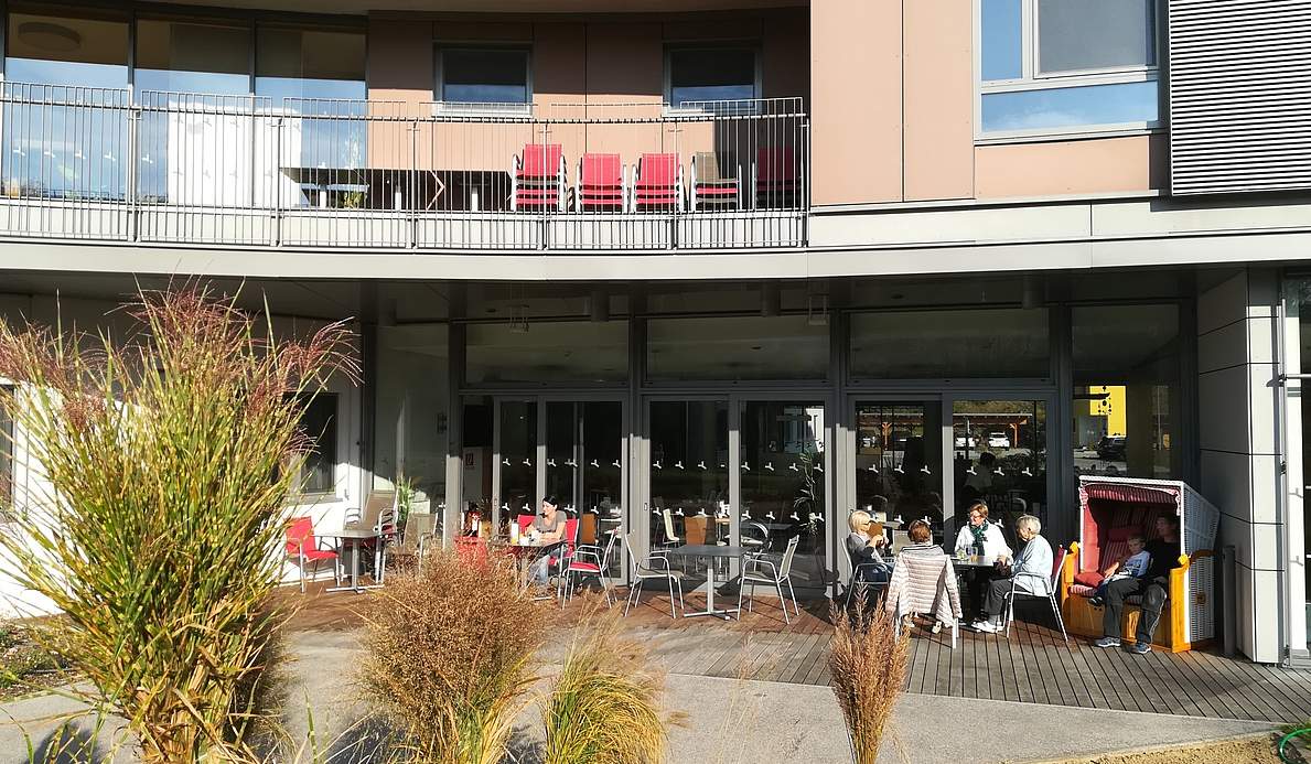 BewohnerInnen sitzen auf der Terrasse des Strandcafes.